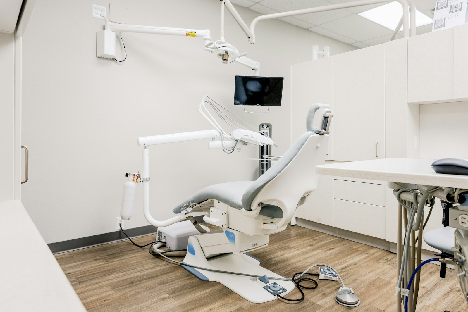 A treatment room with a reclined chair, wood floor and soft daylight